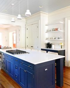 a large kitchen with blue cabinets and white counter tops, along with an island in the middle