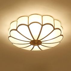 a ceiling light with an intricate design on the top and bottom, against a beige background