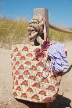 a handbag is sitting on the beach with a rope and sunglasses hanging from it