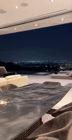 a table and chairs in front of a large window overlooking the city at night time