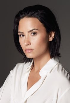 a woman with black hair and white shirt on posing for a magazine cover, she has her arms folded over her chest