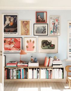 a room with many pictures on the wall and bookshelves in front of it