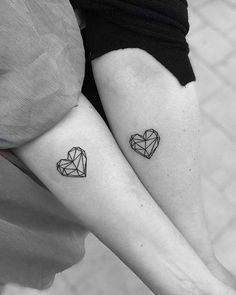 two people with tattoos on their legs, one has a heart and the other has an origami