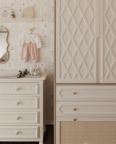 a white dresser sitting next to a mirror on top of a wooden floor