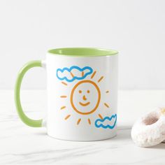 a green and white coffee mug sitting next to a doughnut