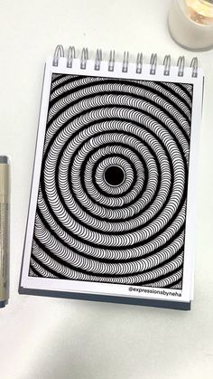 a spiral design is shown on the cover of a spiral notebook next to a battery