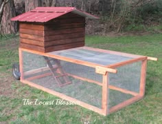 a chicken coop in the grass with a red roof