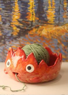 a red bowl with yarn and eyes on it