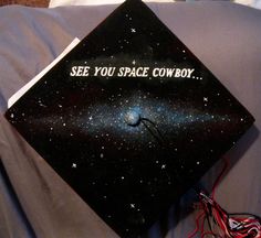 a graduation cap with the words see you space cowboy written in white on it sitting on top of a bed