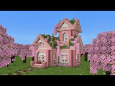 a large pink house surrounded by trees in the middle of a green field with lots of flowers