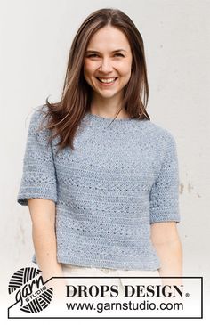 a smiling woman standing in front of a white wall with the words drops design on it