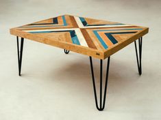 a wooden table with black hairpin legs and a multicolored design on it