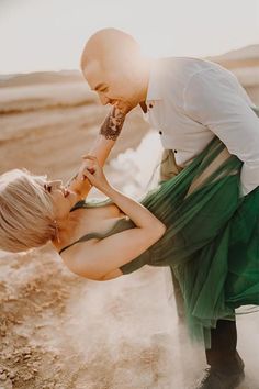 a woman in a green dress and a man in a white shirt are touching each other