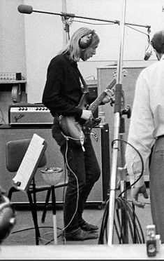 black and white photo of two men playing guitars in a recording studio with microphones