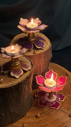 two candles sitting on top of a piece of wood next to each other with flowers