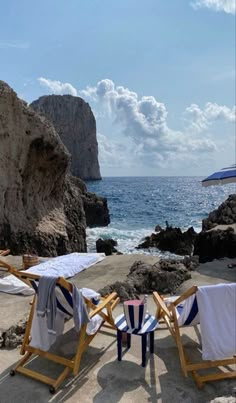 two beach chairs sitting on top of a sandy beach