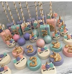 there are many cupcakes on the table with unicorn toppers and candles in them