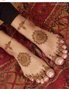 two feet with henna tattoos on them, one is showing off the intricate design