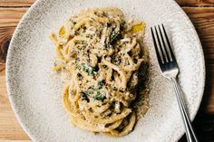 a white plate topped with pasta covered in sauce and parmesan cheese next to a fork