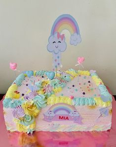 a birthday cake decorated with rainbows and clouds