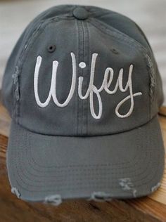 a grey cap with the word wife written on it sitting on top of a wooden table