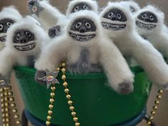 there are many stuffed animals sitting in a green bucket with beads on the handles and feet