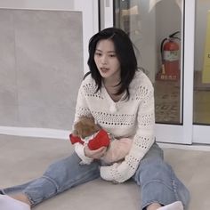 a woman sitting on the floor holding a teddy bear