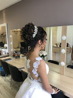 a woman in a wedding dress looking at herself in the mirror while she is getting ready for her big day