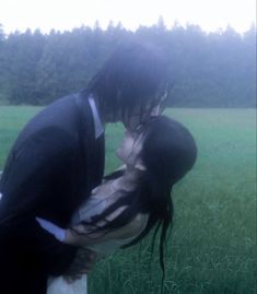 a man and woman kissing in the grass