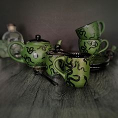 a green tea set with matching cups and saucers sitting on a wooden table top