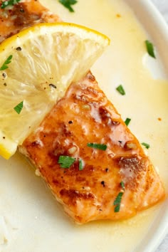 two pieces of fish with lemon and parsley garnish on a white plate