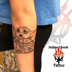 a person with a tattoo on their arm and the image of a baby yoda