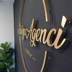 the sign for an office with gold lettering on it's face and back wall