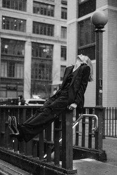 black and white photograph of a woman laying on a rail in the rain with her legs crossed