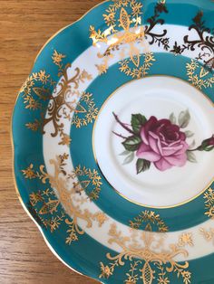 three plates with flowers on them are sitting on a table top, one is blue and the other has gold trimmings