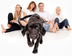 a group of people sitting on the ground with a black dog in front of them