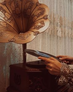 a woman holding a tablet next to an antique record player with intricate designs on it