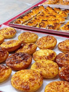 many different types of pastries on display in trays and pans with them