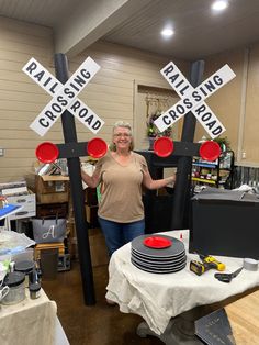 a woman standing next to two railroad crossing signs in a room filled with other items