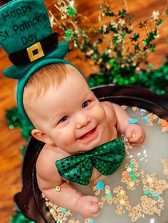 a baby in a st patrick's day outfit sitting on top of a cake