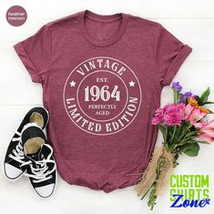 a t - shirt with the words vintage established in white on it next to some flowers