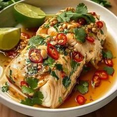 a white bowl filled with fish covered in sauce and garnished with cilantro