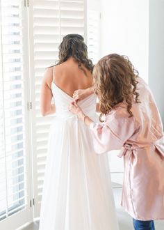 The bride’s mother helped with the final touches, buttoning up her elegant gown in a light-filled room. A beautiful moment filled with love and anticipation before walking down the aisle!