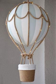 a white hot air balloon hanging from a rope with lights on it's sides