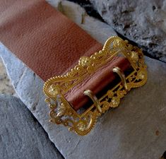 "This Victorian gold filled buckle has been sitting on my desk for 8 years. It is elegantly designed with a scroll and floral motif. I have wanted to make this into a bracelet but just couldn't find the time. I finally experimented with the leather. I chose a very supple leather that will probably darken from wearing and the oils in your skin giving it natural marks. For my first leather bracelet, I am happy with how it came out. The holes are not perfectly aligned but they look pretty good. Wha Elegant Adjustable Belt Buckles With Brass Buckle, Elegant Adjustable Belt Buckle With Brass Detail, Formal Gold Engraved Belt Buckles, Elegant Brown Belt Buckles With Brass Hardware, Elegant Engraved Gold Belt Buckles, Elegant Gold Engraved Belt Buckles, Adjustable Engraved Gold Belt Buckles, Adjustable Gold Belt Buckle As Gift, Vintage Gold Belt Buckles As Gift