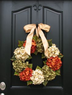 a black door with a wreath and bow hanging on it's front door handle