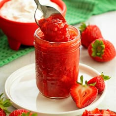 a spoon full of strawberry jam on a plate with strawberries