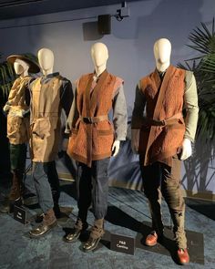 three mannequins dressed in brown and tan clothing, one wearing an orange vest