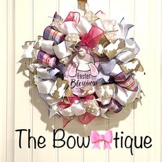 the bowtiquee wreath is hanging on the door with pink and white bows around it