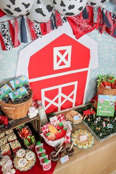 a table topped with lots of food next to a red and white barn sign on top of a wall